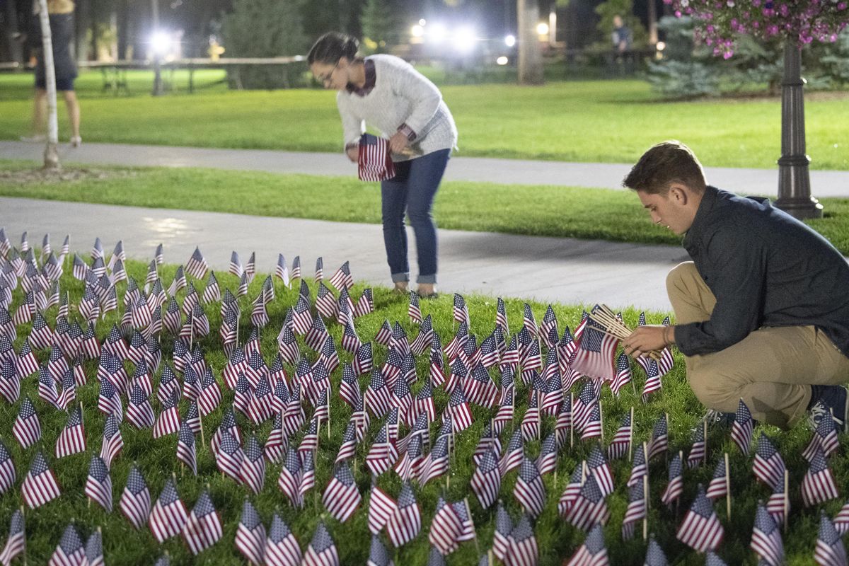 Jake Liening, right, and Mikayla Davis, both students at Whitworth University, gather up some of the hundreds of tiny flags place on the lawn at Whitworth University after a short remembrance program for the 9-11 terrorist attacks on the college campus, Tuesday, Sept. 11, 2018. (Jesse Tinsley / The Spokesman-Review)