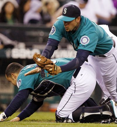 Seattle Mariners third baseman Alex Liddi, right, tumbles over cacher Miguel Olivo after both started for a pop foul from Chicago White Sox's Dayan Viciedo in the third inning of a baseball game Friday, April 20, 2012, in Seattle. Liddi made the catch and held on for the out. (Elaine Thompson / Associated Press)