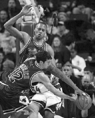 Chicago's Kirk Hinrich (12) swats the ball away from the Seattle SuperSonics' Chris Wilcox, center, while the Bulls' P.J. Brown provides support.
(Associated Press / The Spokesman-Review)