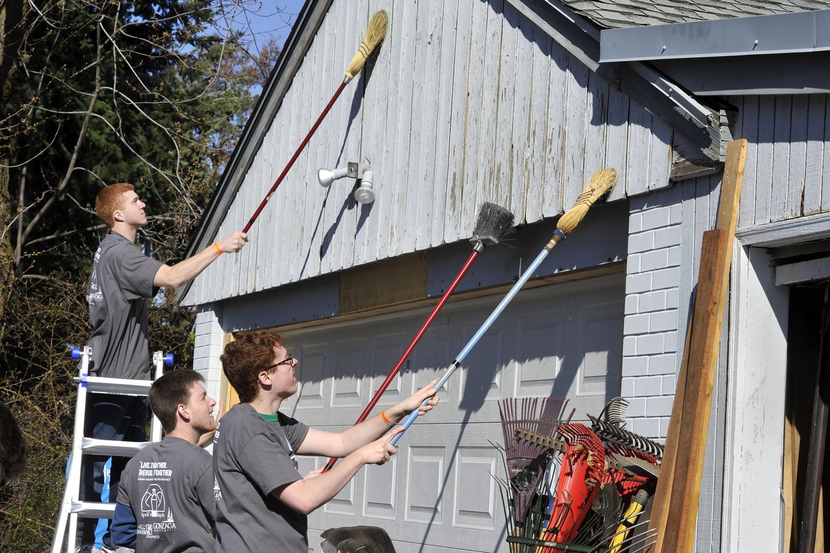 Evan Dobbs, 19, of Nine Mile Falls, Matt Knowels, 18, of Denver, and Casey Kuhnhausen, 21, of Vancouver, Wash., knock paint from a garage Saturday during the Gonzaga University students’ April’s Angels service project at St. Joseph Family Care Center. (PHOTOS BY DAN PELLE)