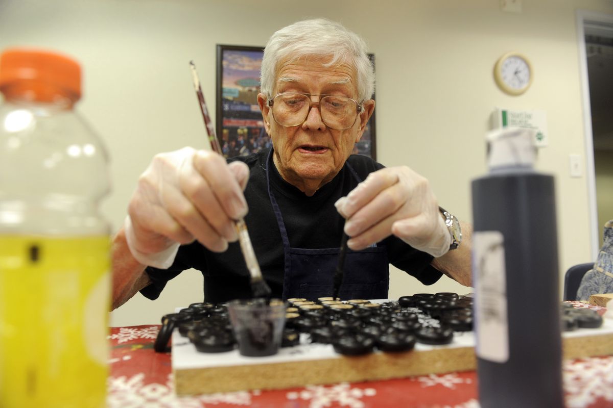 Hugh James, 91, paints hundreds of small wheels for wooden trucks for the Christmas Bureau and other charities at Harbor Crest, a retirement center in Spokane Valley on Wednesday, Dec. 2, 2009. The Hoo Hoo Club has built thousands of the little trucks over the years. (Jesse Tinsley / The Spokesman-Review)