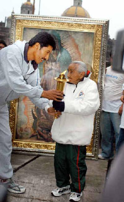 
Rosario Iglesias, 94, hands a torch to Professor Carlos Garcia at the Basilica of the Virgin of Guadalupe in Mexico City on Sunday. 
 (Associated Press / The Spokesman-Review)