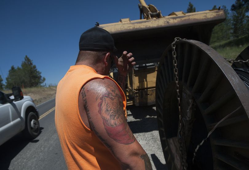 Construction worker Brandon Howell wipes the sweat from his brow while working to lay telephone cable Monday on Swenson-Williams Valley Road in Nine Mile Falls. (Tyler Tjomsland)