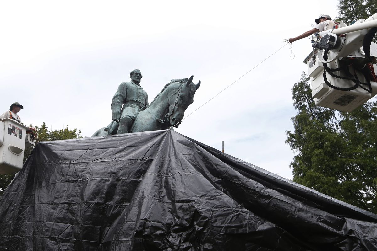 FILE - In this Wednesday, Aug. 23, 2017 file photo, city workers drape a tarp over a statue of Confederate Gen. Robert E. Lee in Emancipation park in Charlottesville, Va., intended to symbolize the city