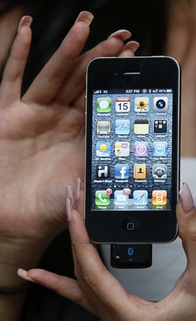 A model holds the iPhone 4 with Bluetooth device during a promotional event in Hong Kong on Thursday. (Associated Press)