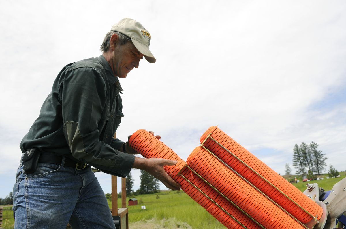 Dave Arnold, of Vancouver, Wash., loads clay targets onto the launcher during  the Washington State Sporting Clays Championships held at Landt Farms in June.  (Photos by Dan Pelle / The Spokesman-Review)