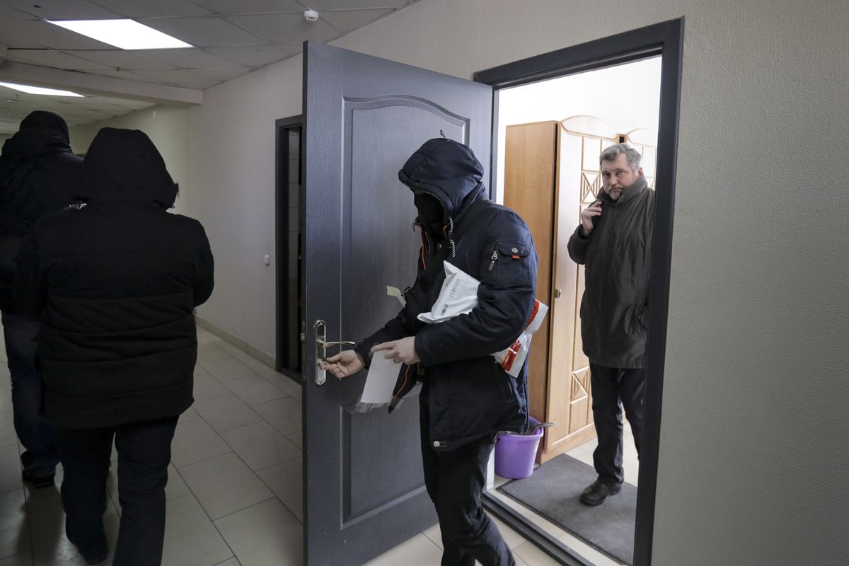 Police carry documents and computers out of the office of the Belarusian Association of Journalists as Andrei Bastunets, the head the Association, right, stands inside the office in Minsk, Belarus, Tuesday, Feb. 16, 2021. Authorities in Belarus have raided the homes and offices of journalists and human rights activists. It is the latest move aimed at squelching a wave of demonstrations against authoritarian President Alexander Lukashenko. Police searched the offices of the Belarusian Association of Journalists and the Viasna human rights center, as well as the apartments of its members.  (STR)