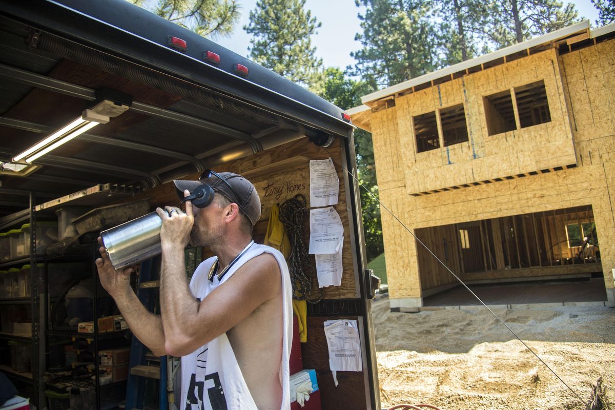 Construction worker Mike Schanuth hit the shade and a jug of water after roofing a new home at the corner of 13th Avenue and Lacey Street in Spokane, Wash. “It’s like being in a sauna (on the roof)” says Schanuth as temperatures soared into the high 90s. (Dan Pelle / The Spokesman-Review)