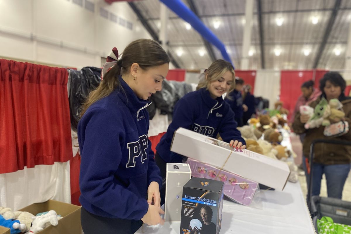 Cheerleaders Genevieve Meany and Cora Thomas help bag clients