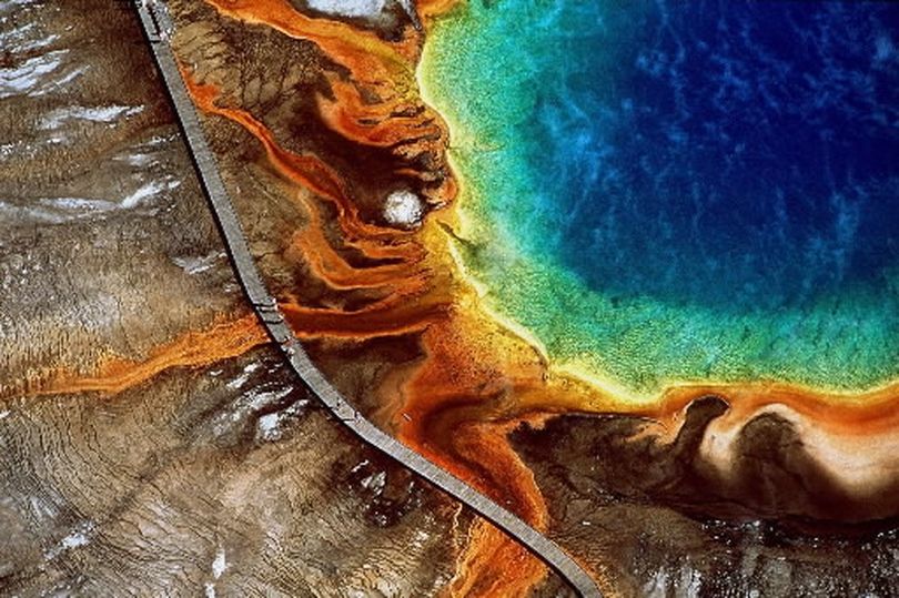 Tourists walk along the boardwalk at the edge of the Grand Prismatic Spring in Yellowstone National Park, Wyoming, in this aerial photo shot from a manned aircraft, date unknown.  (Yann Arthus-Bertrand)
