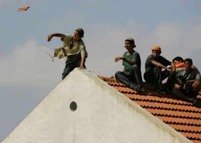 A Jewish settler barricaded on the rooftop of a house throws a roof tile on Israeli security forces, not seen, attempting to evacuate the Jewish settlement of Gadid, in the southern Gaza Strip on Friday. 
 (Associated Press / The Spokesman-Review)