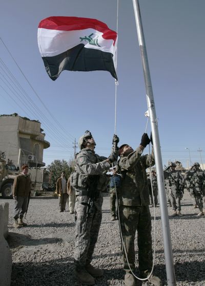 U.S. and Iraqi soldiers raise Iraq’s flag during a ceremony in which Iraqi forces took control of the Joint Security Station in the Ghazaliyah neighborhood of Baghdad on Thursday.  (Associated Press / The Spokesman-Review)