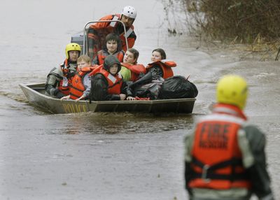 Residents leave a flooded neighborhood Wednesday along McCutcheon Road near Orting, Wash. The rising Puyallup River forced hundreds  from their homes.  (Associated Press / The Spokesman-Review)
