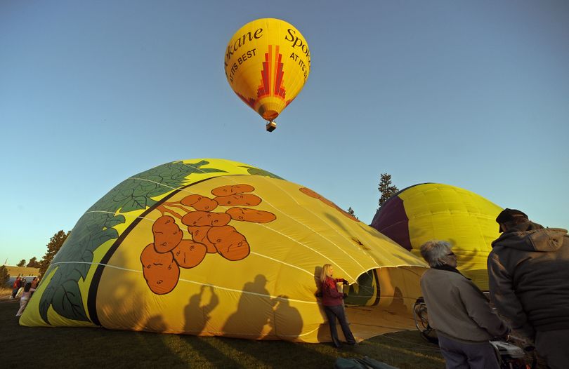 Festive air: Hot air balloons lift off from CenterPlace Event Center at dawn Saturday as part of Balloons Over Valleyfest. A balloon named “Spuds,” operated by Stephanie Hughes, of Spokane, is being filled as another lifts off toward the east. (Christopher Anderson)