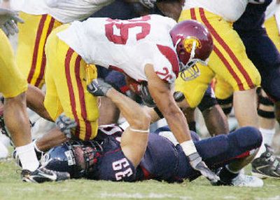 
Arizona's Dane Krogstad tackles USC's Emmanuel Moody.
 (Associated Press / The Spokesman-Review)