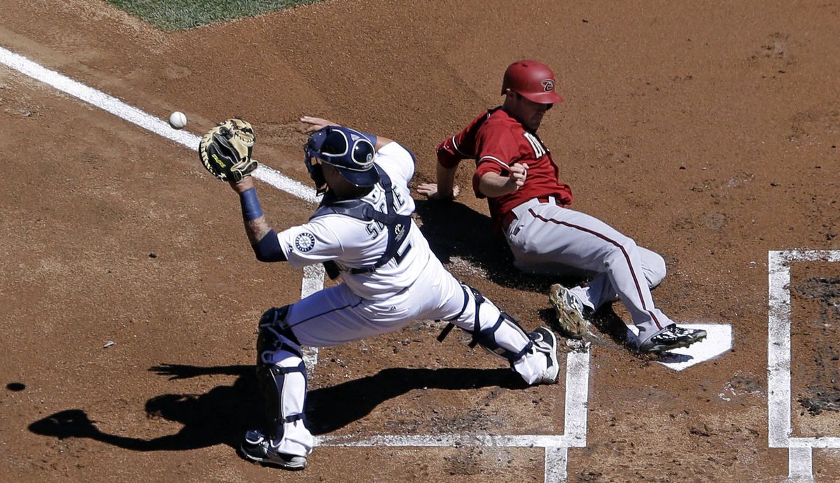 Arizona’s A.J. Pollock crosses home ahead of throw to Seattle catcher Jesus Sucre in first inning. (Associated Press)