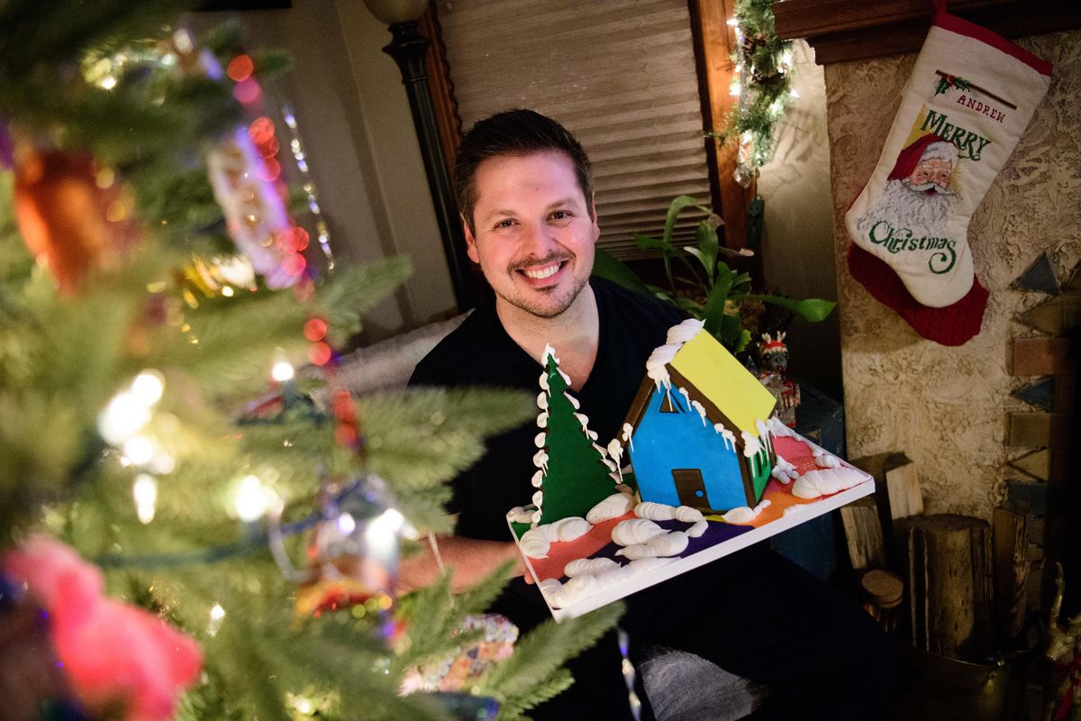 Spokane chef and baker Ricky Webster sits with one of his gingerbread houses on Dec. 3 at his home in Spokane. (Tyler Tjomsland / The Spokesman-Review)