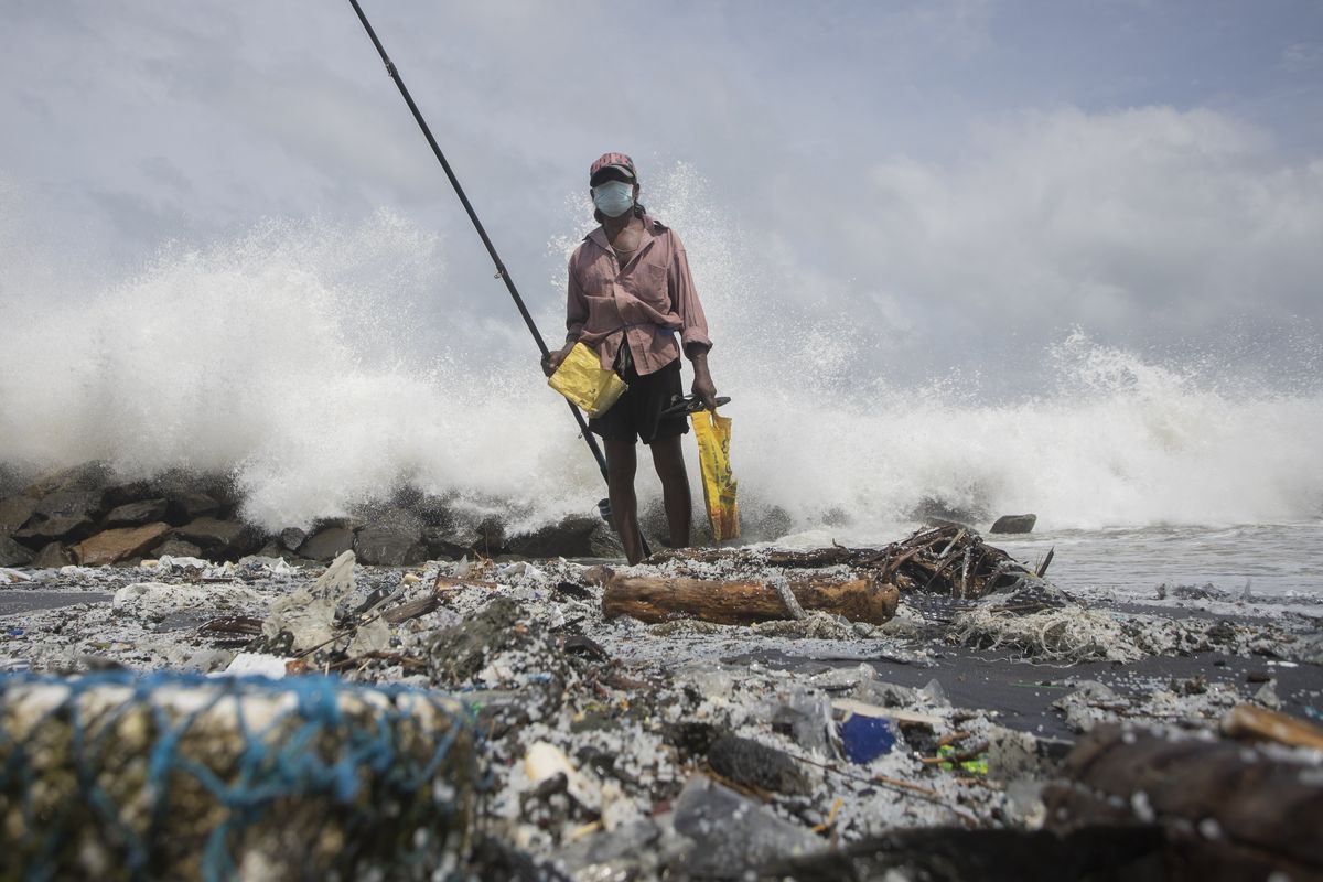 Kindston Jayalath fishes on a polluted beach filled with plastic pellets washed ashore from the fire-damaged container ship MV X-Press Pearl on Friday on the outskirts of Colombo, Sri Lanka.  (Eranga Jayawardena)