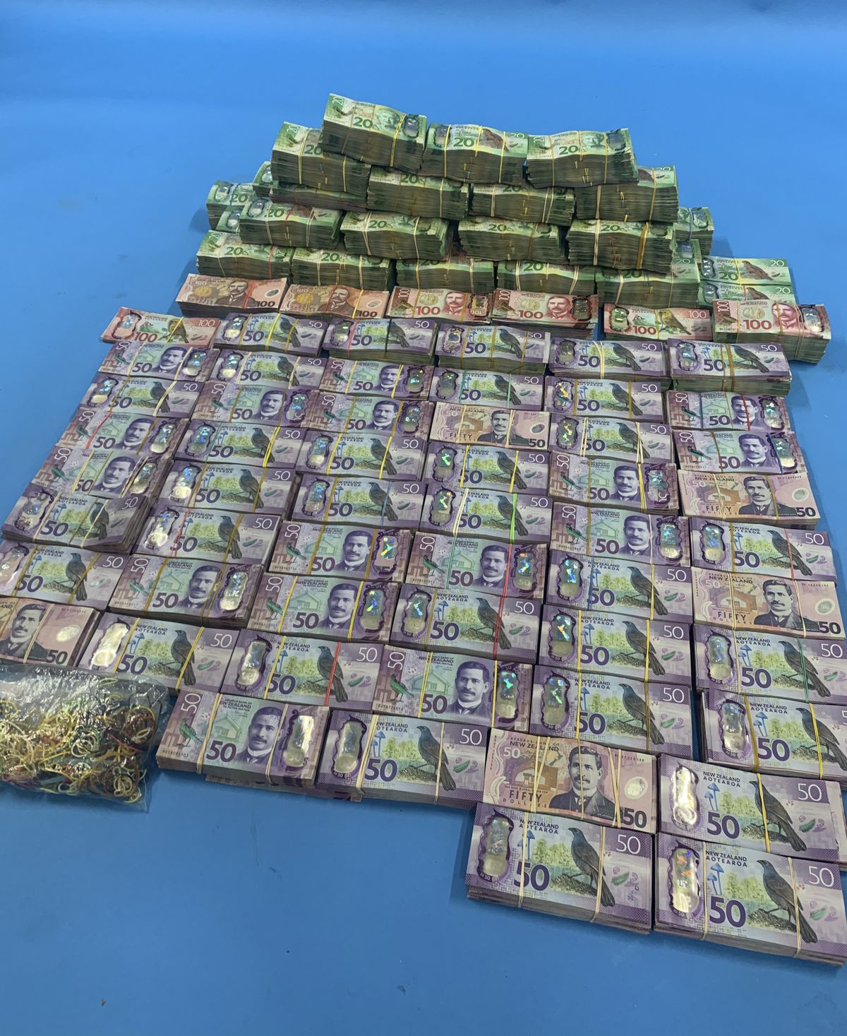 In this undated photo supplied by the New Zealand police, a large amount of cash is displayed during a police raid as part of Operation Trojan. Authorities in Australia and New Zealand said Tuesday, June 8, 2021, they've dealt a huge blow to organized crime after hundreds of criminals were tricked into using a messaging app that was being secretly run by the FBI.  (NZ POLICE)