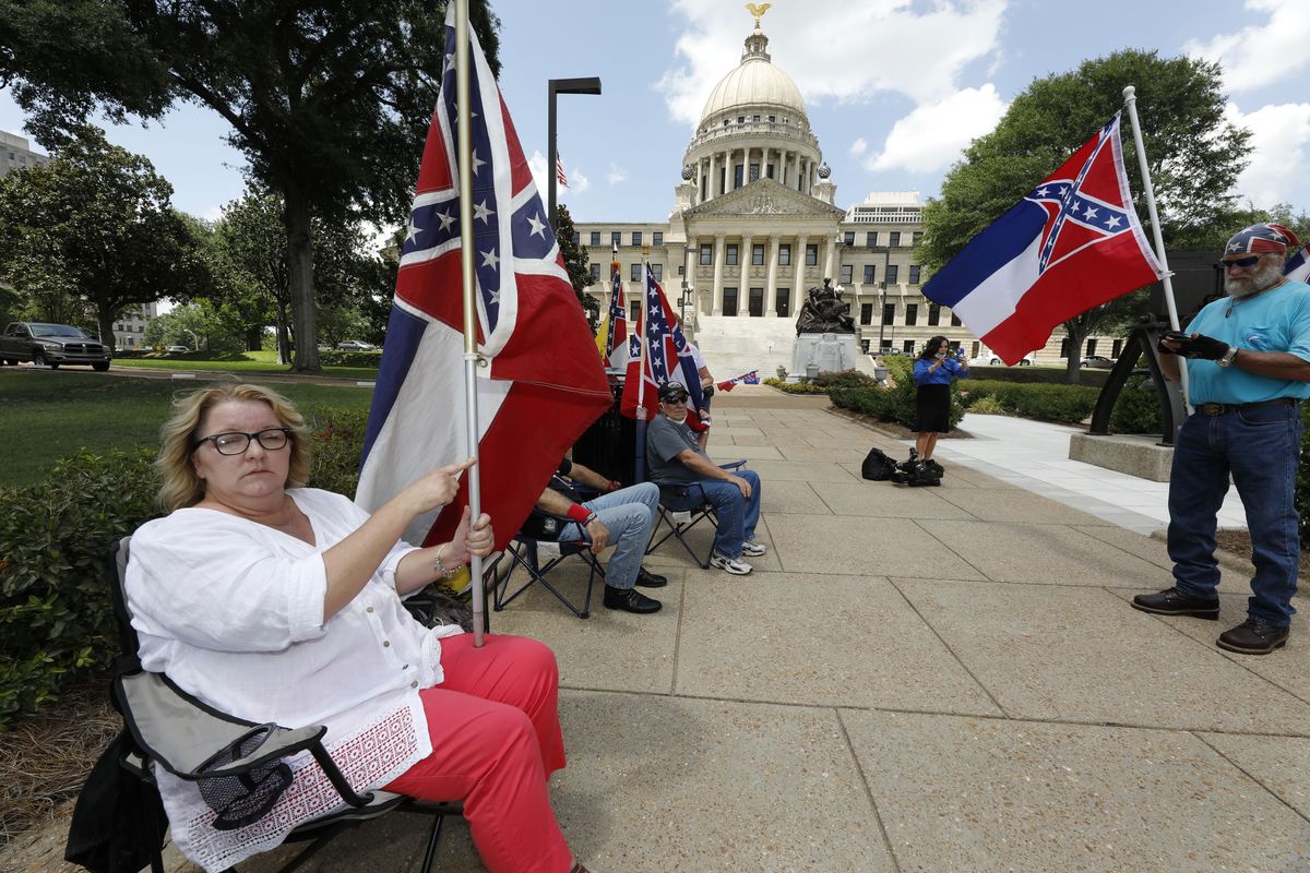 Tessa Collett of Petal, left, wants her vote to count as she supports the current flag as do other supporters standing outside the state Capitol in Jackson, Miss., Sunday, June 28, 2020. Lawmakers in both chambers are expected to debate state flag change legislation today. Mississippi Governor Tate Reeves has already said he would sign whatever flag bill the Legislature decides on.  (Rogelio V. Solis)