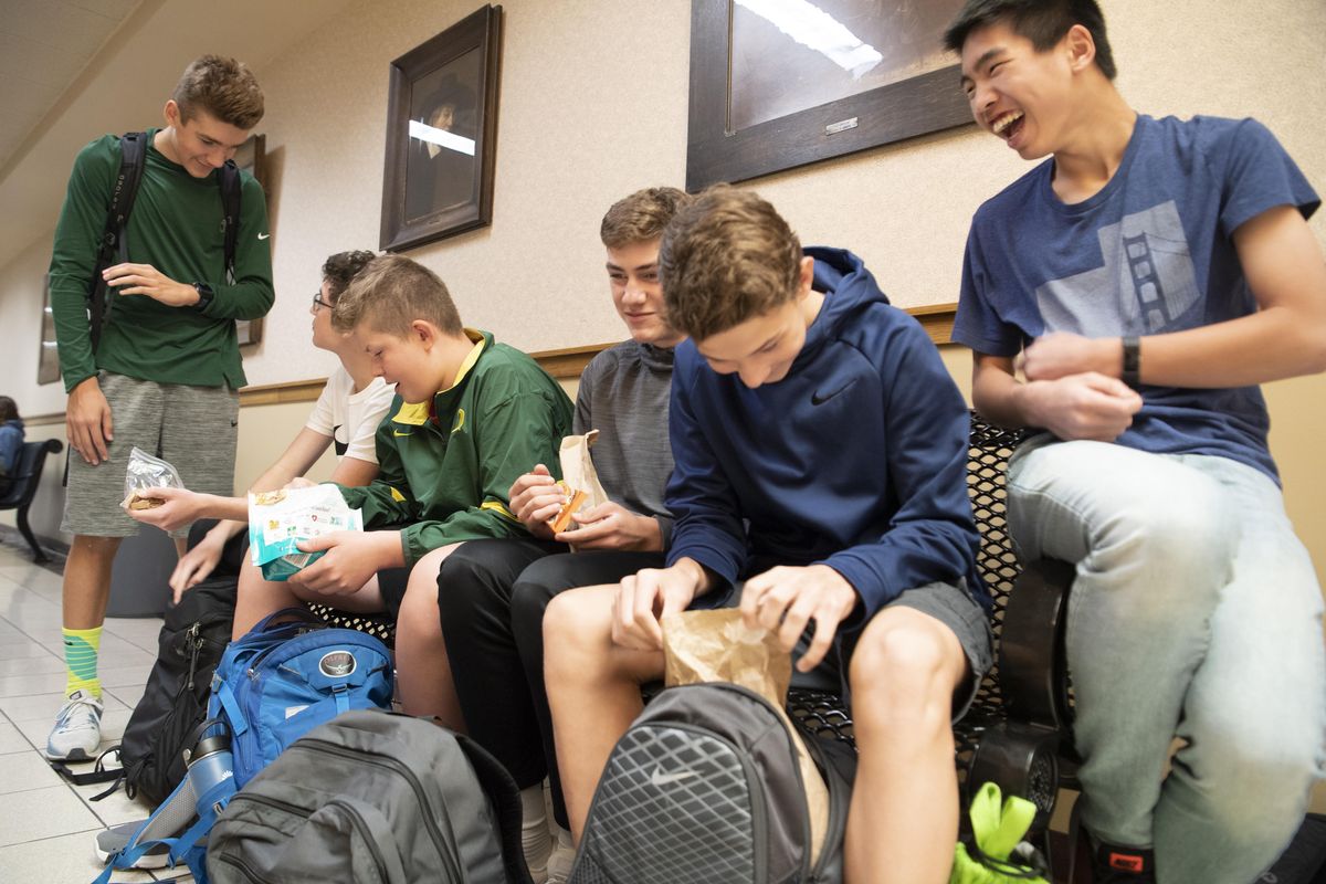 Freshmen, from left, Jackson Storey, Liam Kerkering, Jack Parker, Blake Mitchell, Brady Smith, and Ben Loke crowd onto a bench in the hallway to eat lunch Tuesday, Sept. 25, 2018 at Lewis and Clark High School. The school bond on the November ballot contains funds to add a lunchroom to the urban high school which has never had one. (Jesse Tinsley / The Spokesman-Review)