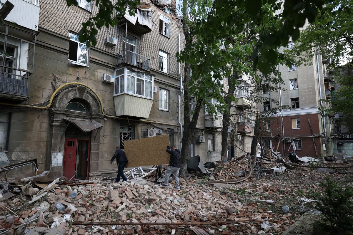 Local residents carry a wooden sheet to cover a broken window in a residential building damaged as a result of a missile attack in Dnipro on April 19, 2024, amid the Russian invasion of Ukraine. Russian strikes against Ukraine on Friday killed at least eight people, including two children, as Kyiv said it shot down a Russian strategic bomber for the first time.  (Anatolii Stepanov/AFP/Getty Images/TNS)