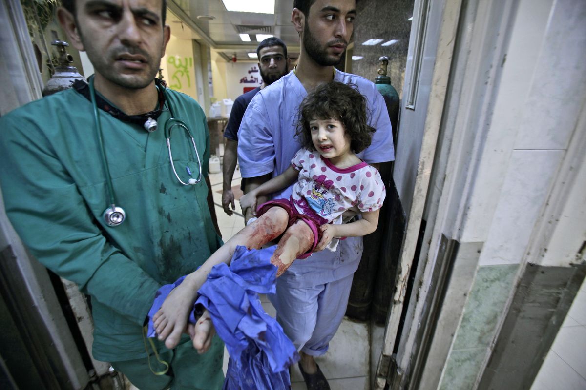 Medics carry Fatima Qassem, 6, whose legs were badly injured when government forces fired on her family