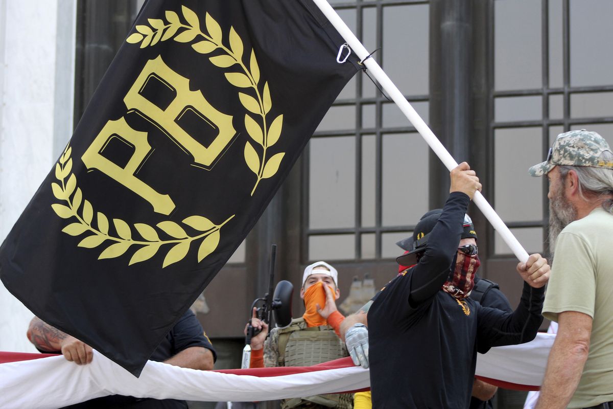FILE - In this Sept. 7, 2020, file photo, a protester carries a Proud Boys banner, a right-wing group, while other members start to unfurl a large U.S. flag in front of the Oregon State Capitol in Salem, Ore. The Canadian government designated the Proud Boys group as a terrorist entity on Wednesday, Feb. 3, 2021, noting they played a pivotal role in the insurrection at the U.S. Capitol on Jan. 6. (Andrew Selsky)