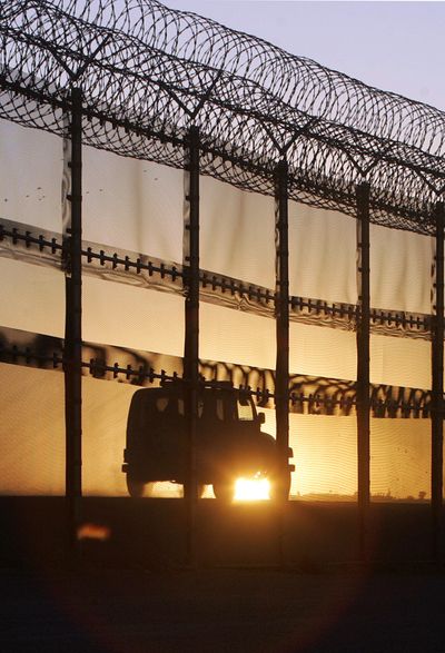 A Border Patrol vehicle speeds along the border fence with concertina wire topping at sunset  in San Diego on Monday.  Critics say the prison-style fence is an eyesore. (Associated Press / The Spokesman-Review)