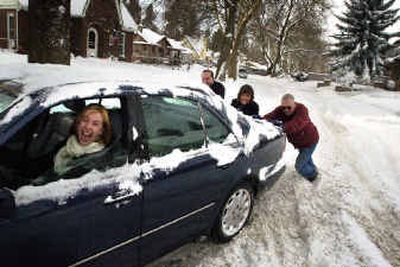 
Lisa Ruiz, 30, of Seatlle makes the most out of being stuck in the snow Saturday morning as, from left, her husband, Bernnardo, mother Angelika Tann and neighbor Don Willingham help push her at the intersection of Bernard and 20th. Ruiz was raised in Spokane, and said, 