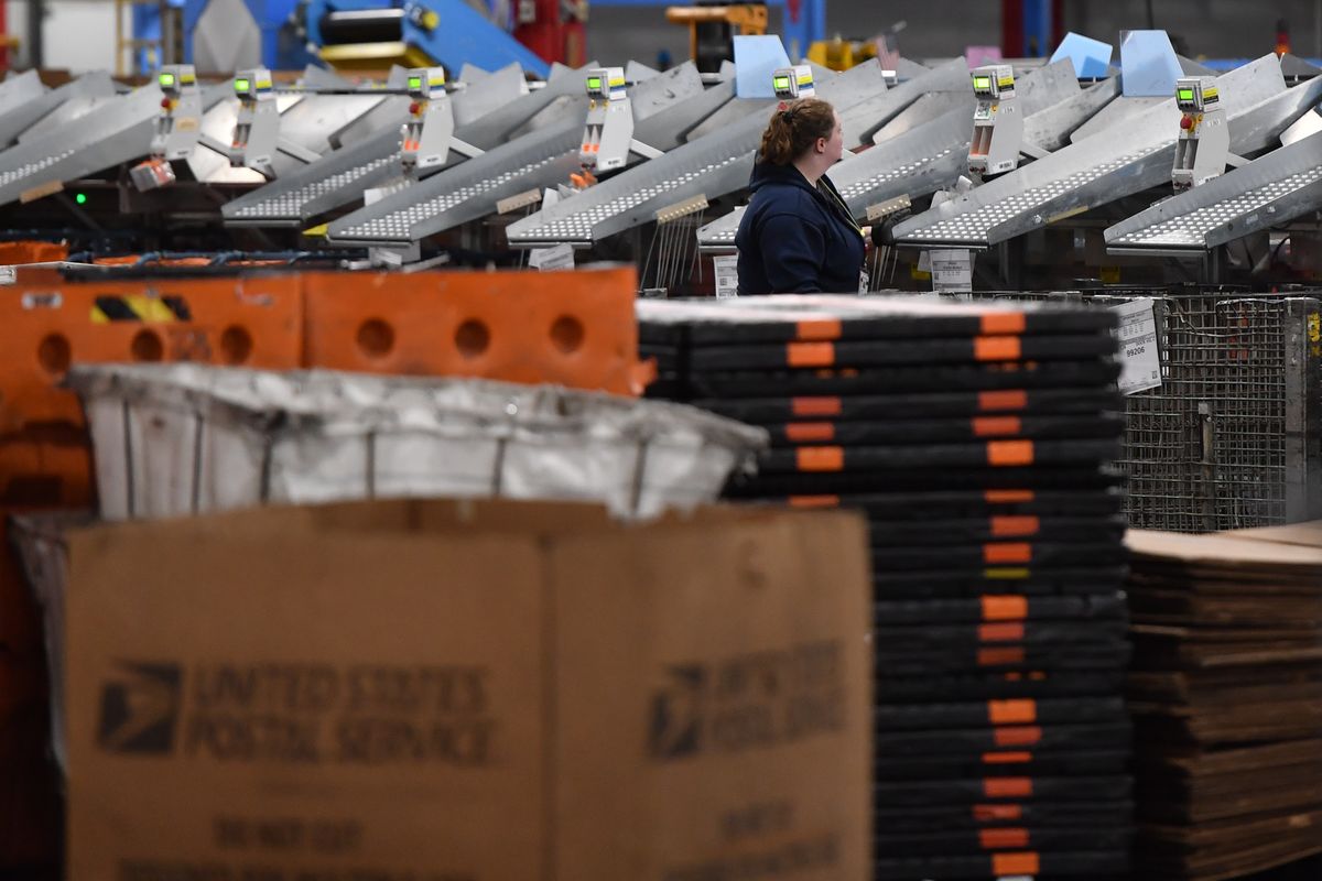 Postal workers sort through package at the USPS processing and distribution center.  (Tyler Tjomsland/The Spokesman-Review)