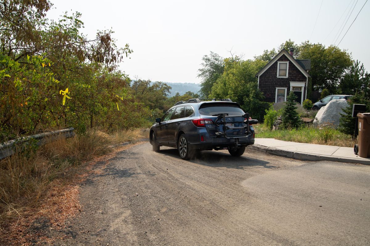 A car drives down an unpaved road on Friday, Aug. 10, 2018 between the 1900 and 2000 block of Falls Avenue, where the city will spend about $300,000 in fees from car tabs to pave the road to 16 historic homes in the West Central neighborhood. The Spokane City Council signed off on the project last year despite a citizen oversight board determining the project wasn