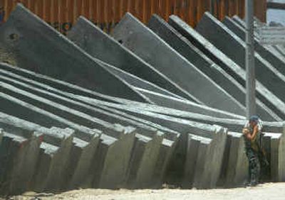 
An Israeli security guard stands on Monday next to 8-meter-high concrete blocks that will be used in the construction of Israel's controversial security barrier next to the town of A-Ram on the outskirts of Jerusalem. This section will separate thousands of Palestinians from their workplaces, schools and families in Jerusalem.
 (Associated Press / The Spokesman-Review)