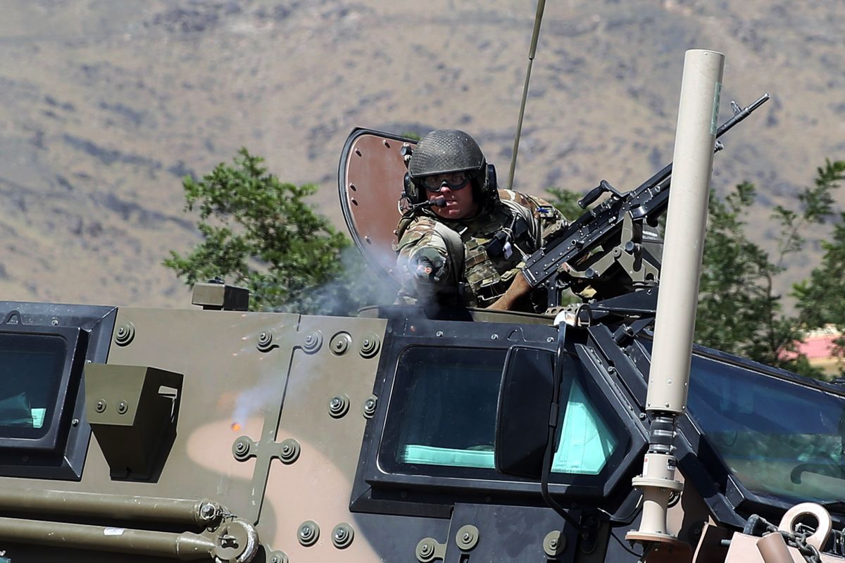 A NATO soldier fires an apparent warning shot in the vicinity of journalists near the main gate of Camp Qargha, west of Kabul, Afghanistan, on Tuesday. (Associated Press)