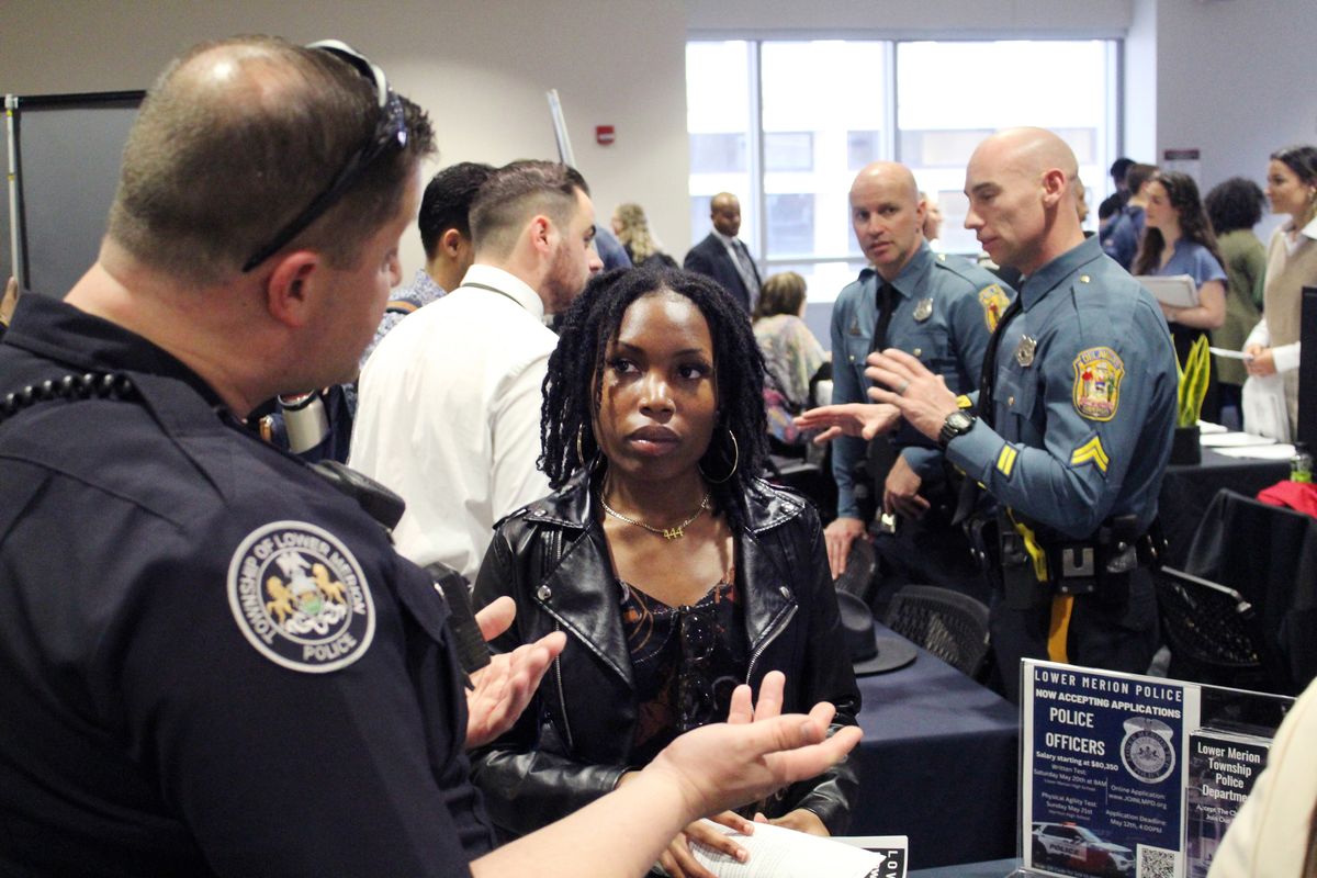 A police officer in Lower Merion, Pa., talks with Temple University senior Justice Henry during a recruiting event on March 4 at the Philadelphia school. She hopes to become a criminal defense attorney.  (Robert Klemko/The Washington Post)