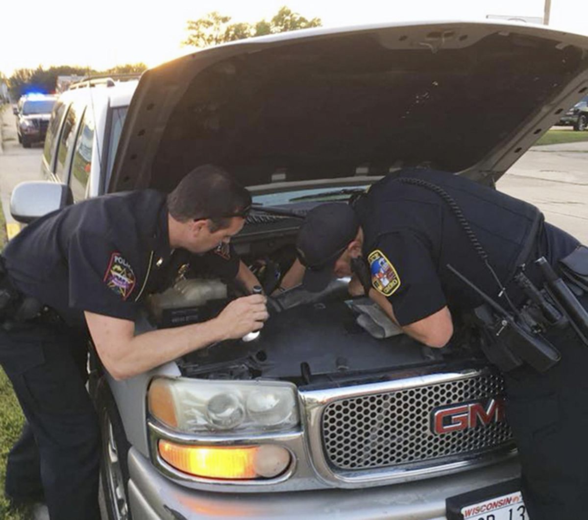 This Wednesday, Aug. 22, 2018, photo provided by the Omro Police Department in Omro, Wis., shows police officers trying to remove a 4-foot-long Ball python that was discovered wrapped around a car engine. It took hours to unwind and coax the snake from the engine compartment. Police say the snake escaped from its owner more than a month ago. (AP)