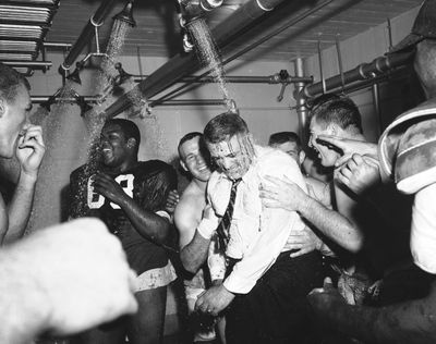 Ohio State football coach Woody Hayes, center, gets a clothes-on dunking in the Ohio State dressing room shortly after Ohio State University won the Big Ten championship and clinched a Rose Bowl bid by defeating Iowa 17-13, in Columbus, Ohio, during November 1957. (Associated Press)