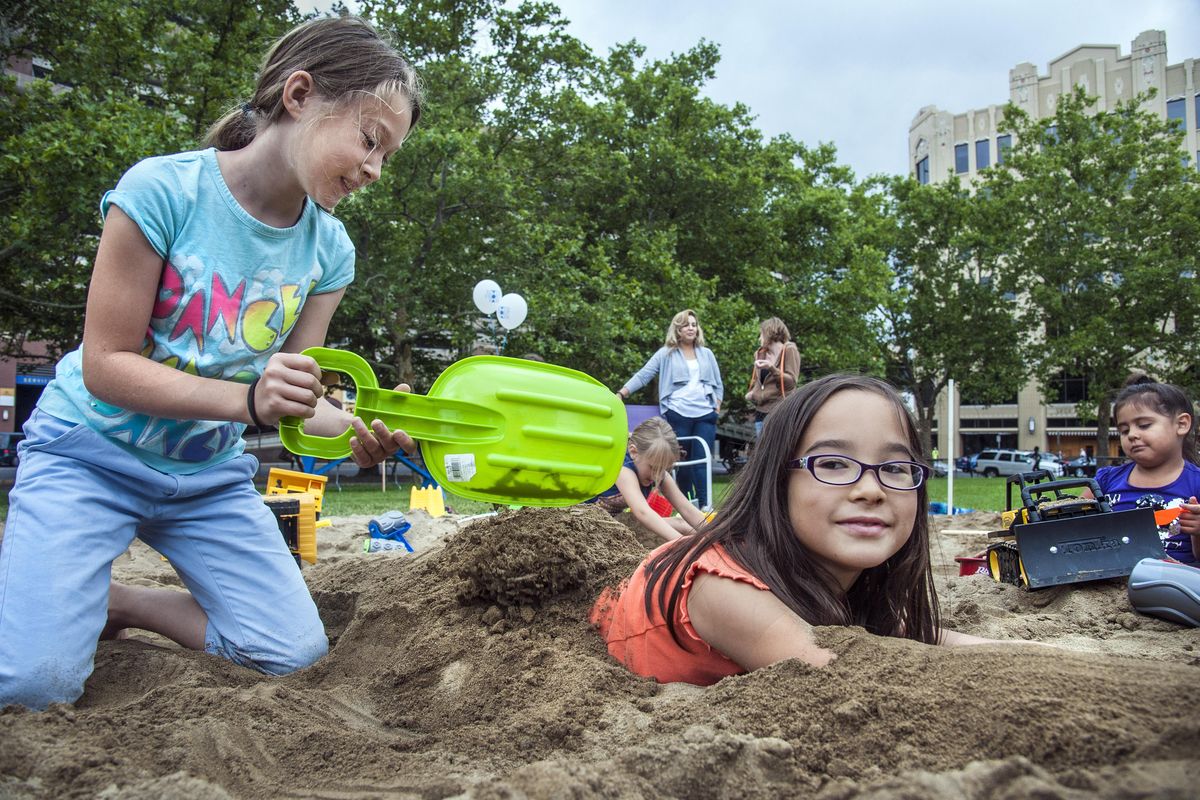 Serena Takekoshi, left and her sister Lela, of Manchester, New Hampshire, are up to their knees and elbows in fun as they play in the 30-ton sandbox in the Gondola Meadow, July 8, 2016, in Riverfront Park. A kickoff celebration for construction of the park’s renovation also included a beer garden, live music, and a field of ping pong tables painted by local artists. An ice ribbon skating rink is planned for the area of the sandbox. (Dan Pelle / The Spokesman-Review)