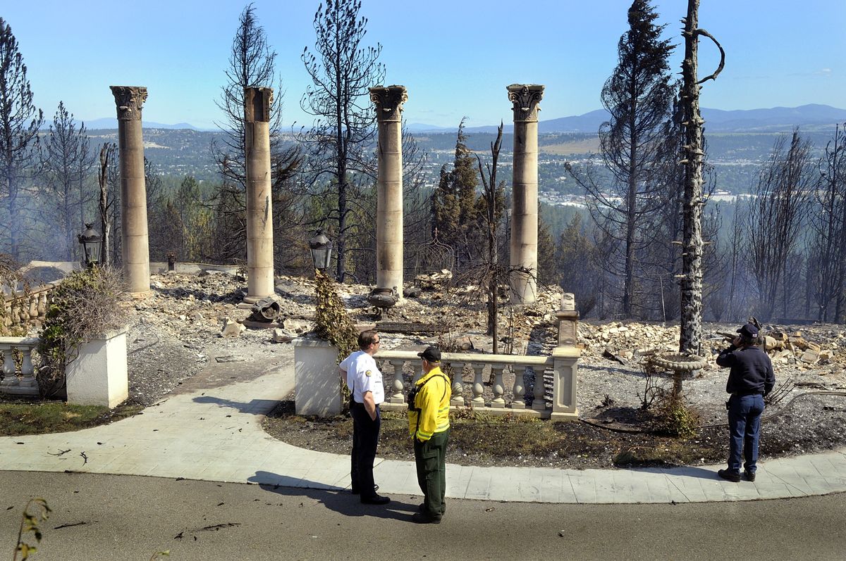 Thursday’s wildfire destroyed this eight-bedroom home owned by the widow of Tim Pring, president of Spokane’s Appleway Group of auto dealerships. Spokane Valley fire personnel examine the remains.   (Photos by CHRISTOPHER ANDERSON / The Spokesman-Review)