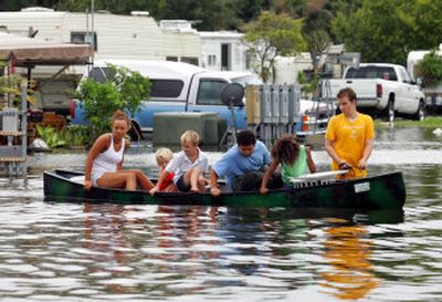 
Jordan Hale, front, pulls kids in a canoe through a flooded mobile home park in Florida City, Fla., Friday. Hurricane Katrina flooded streets, darkened homes and felled trees as it plowed across South Florida. 
 (Associated Press / The Spokesman-Review)