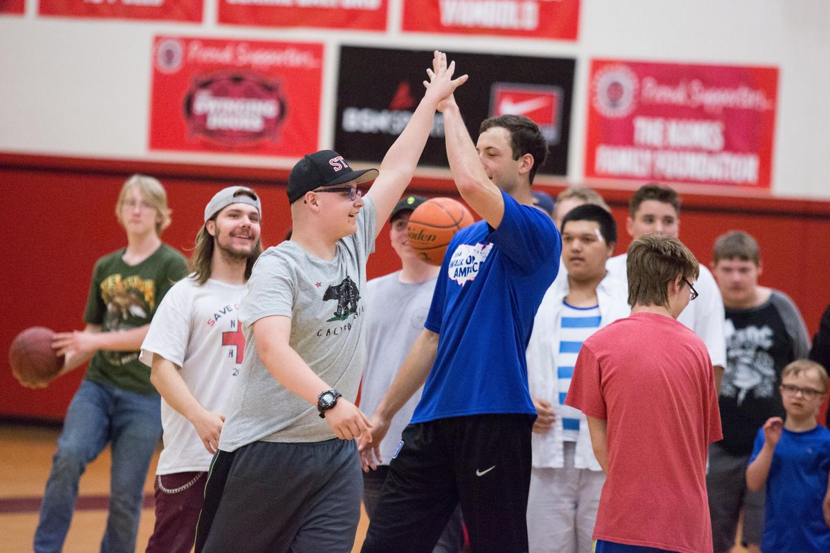 Liam Parlange, left, receives a high-five from Brennan Besser after hiittng a half-court shot during the Walk On America basketball clinic that Besser directed Tuesday at North Central High School. (Libby Kamrowski / The Spokesman-Review)