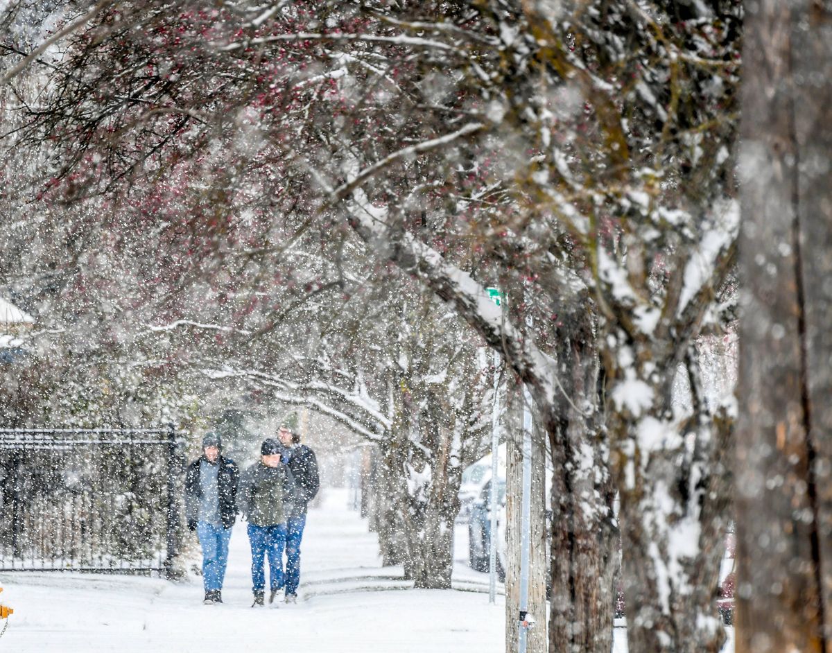 Pedestrians are blanketed by snow as they walk along Astor Street during Monday