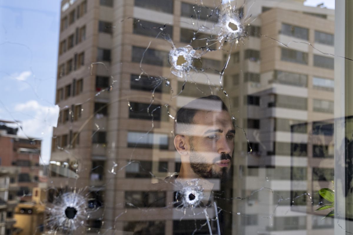 An employee looks through an office window riddled with bullet holes after the deadly clashes that erupted last Thursday along a former 1975-90 civil war front-line between Muslim Shiite and Christian areas, in Ain el-Rumaneh neighborhood, Beirut, Lebanon, Tuesday, Oct. 19, 2021. The shootout on the streets of Beirut between rival Christian and Muslim groups has revived memories of the country