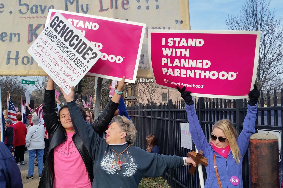 A Planned Parenthood supporter and opponent try to block each other