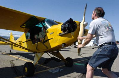 
Jack Hohner gives the propeller a turn on a Piper Cub on Saturday at Felts Field as pilot Charles Britt waits to take his passenger, Nate Pickette, 9, on a flight. 
 (Dan Pelle / The Spokesman-Review)