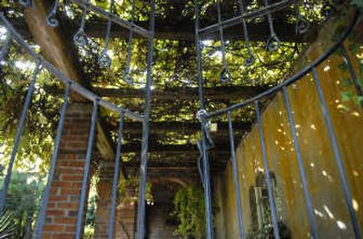 
An iron gate opens to a grapevine-covered patio at Al and Vikkie Naccarato's  historic Millwood home. The 1923 home, below, will be included in the Historic Millwood Walking Tour Saturday and Sunday.
 (Photos by Holly Pickett / The Spokesman-Review)