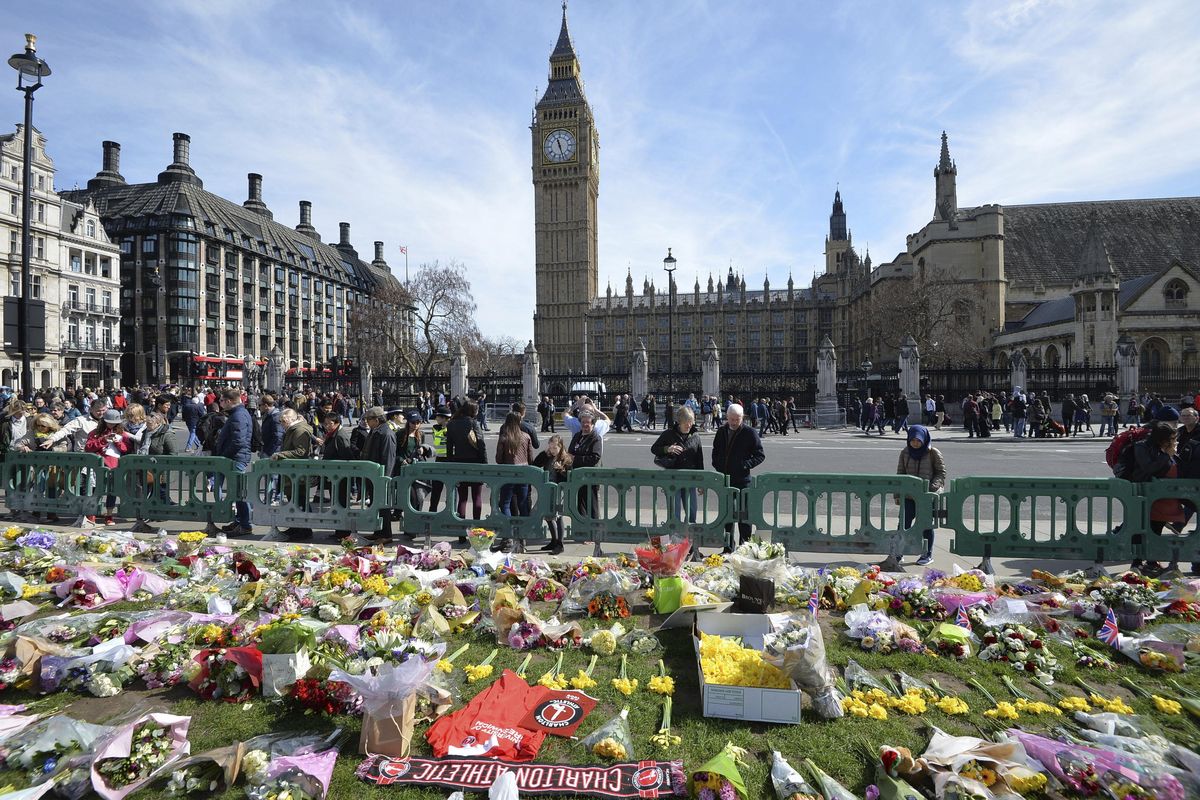 People look at tributes in Parliament Square, London, on Saturday, laid out for the victims of the Westminster Bridge attack on Wednesday. Khalid Masood killed four people and left more than two dozen hospitalized, including some with what have been described as catastrophic injuries. The Islamic State group claimed responsibility for the attack. (John Stillwell / Associated Press)