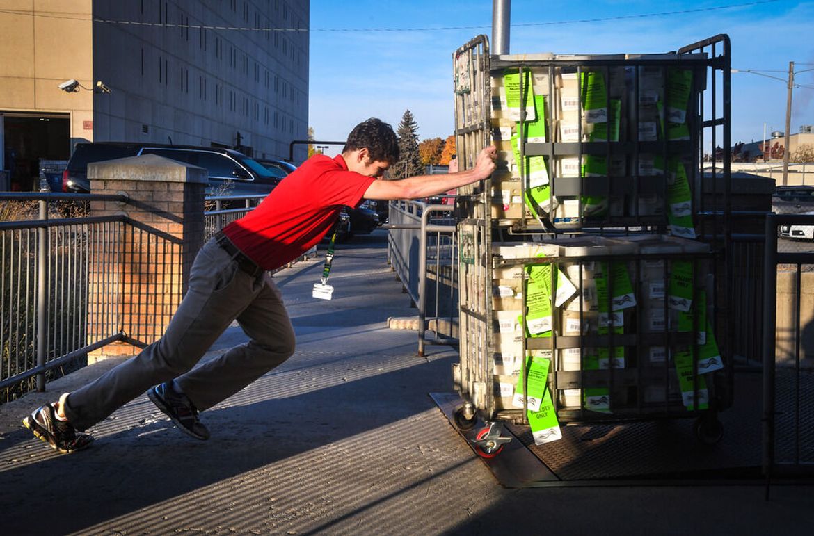 Ryan Dosch, voter services specialist at the Spokane County Elections Office, rolls a cart weighting 840 pounds with ballots into a Ryder truck headed to the post office on Oct. 18, 2018. The Secretary of State’s office issued an emergency rule Wednesday requiring county election officials to use first-class postage to mail ballots. (DAN PELLE) 