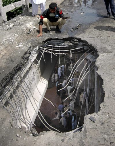 A Pakistani police officer looks down through a hole created by a bomb explosion on an overpass in Peshawar, Pakistan, on Tuesday.  (Associated Press / The Spokesman-Review)