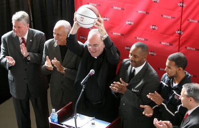 Seattle U president Father Stephen Sundborg holds up a basketball during a news conference announcing the team’s move to KeyArena. (Associated Press / The Spokesman-Review)